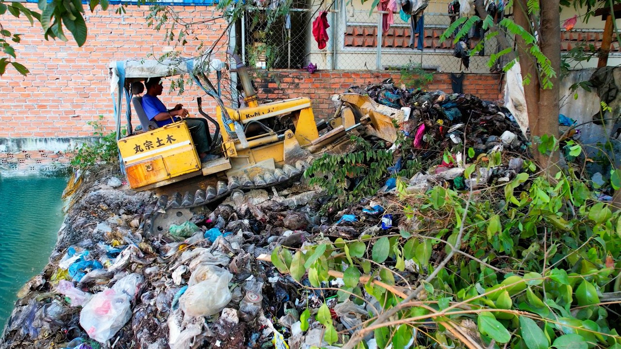 Bulldozer push the mountain trash and dump truck transport the stone for unload