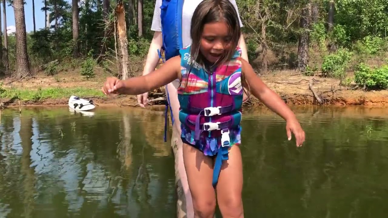 Kids balance on a log at the lake