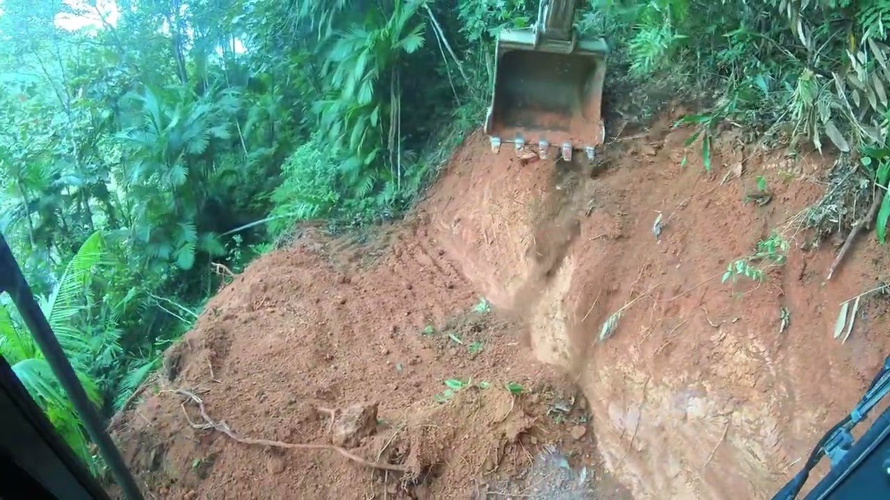 escavadeira abrindo estrada em cima de barreiras