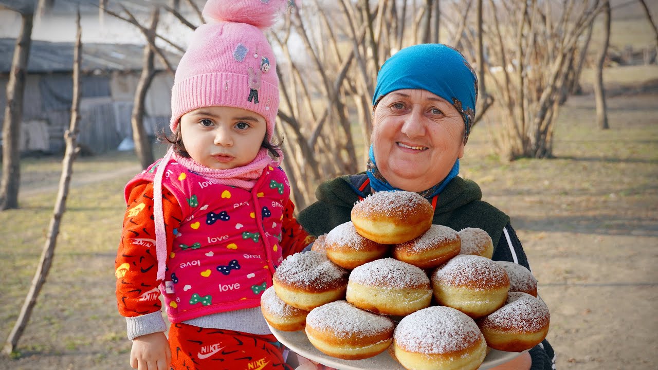 Бабушка с внучкой готовят сахарные пончики и фаршированную печень в деревне