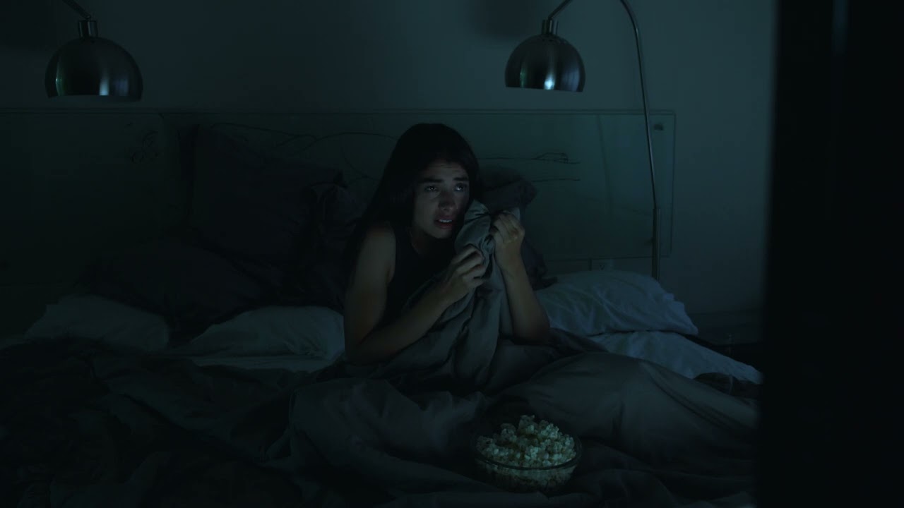 mixkit girl watching a horror movie in her bedroom with the 25580