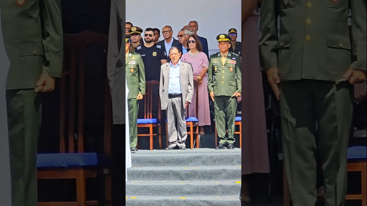 Todos de pé. O Pavilhão Nacional vai adentrar o pátio da Escola de Sargentos das Armas.