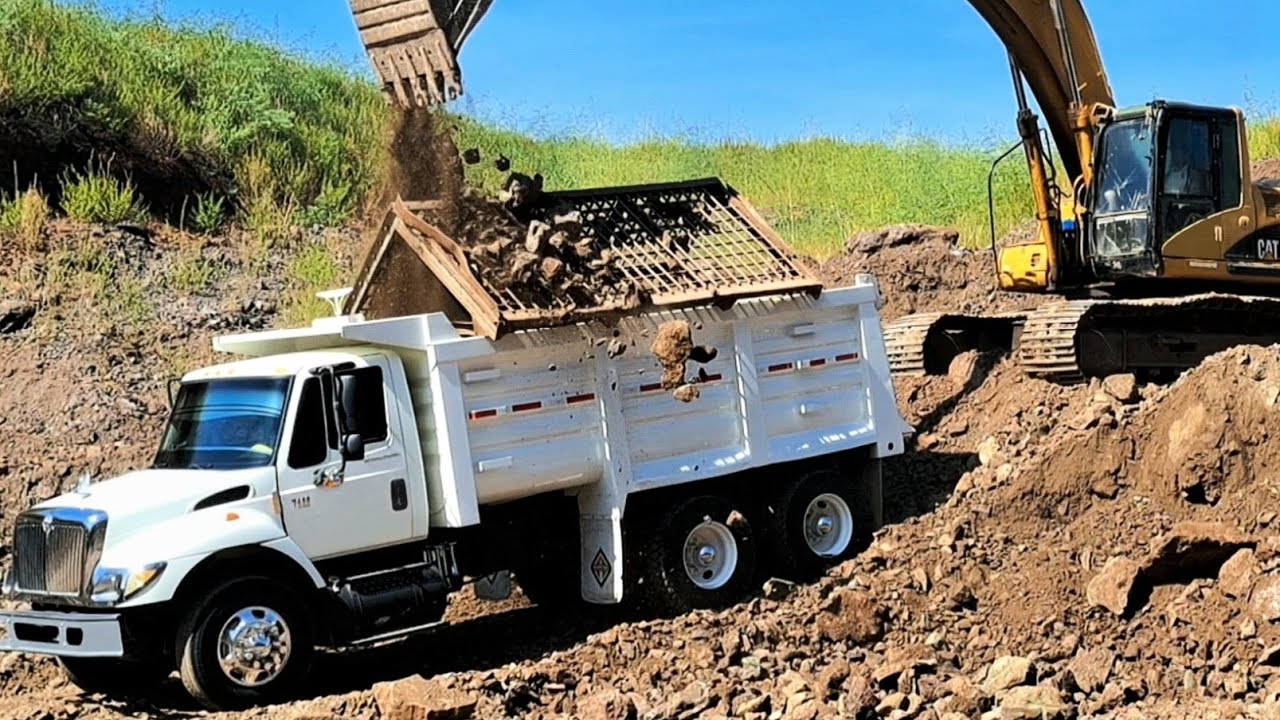 Excavadora CAT 330CL cargando camiones de volteo International de 7 m³ y 14 m³