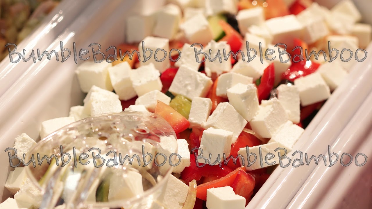 Colorful fresh vegetable salad with feta cheese in a white deep bowl closeup in the dispensing