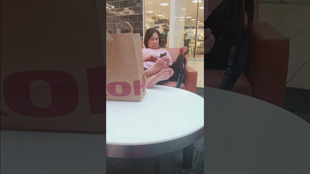 Old asian lady puts her bare feet up in public to take a break from shopping