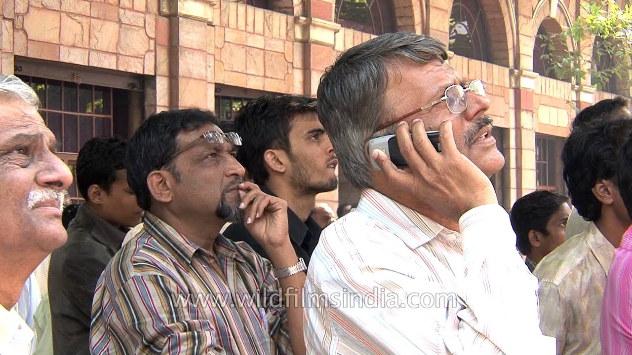 People look at a large screen displaying India's benchmark share index