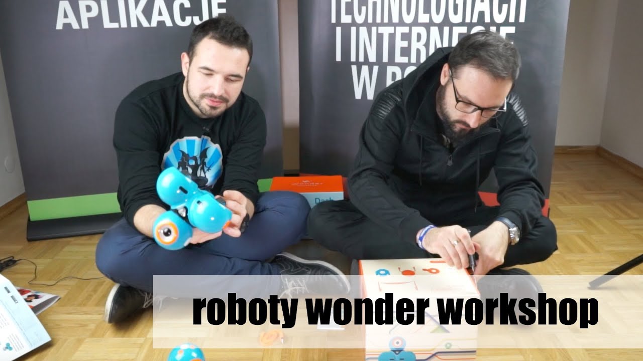 Dwóch dorosłych facetów siedzi i wypakowuje robociki Wonder Workshop