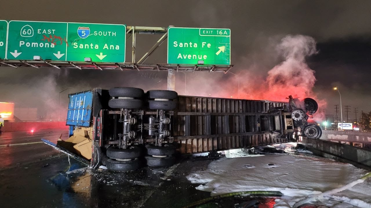 Tractor dangles off freeway while container is on fire