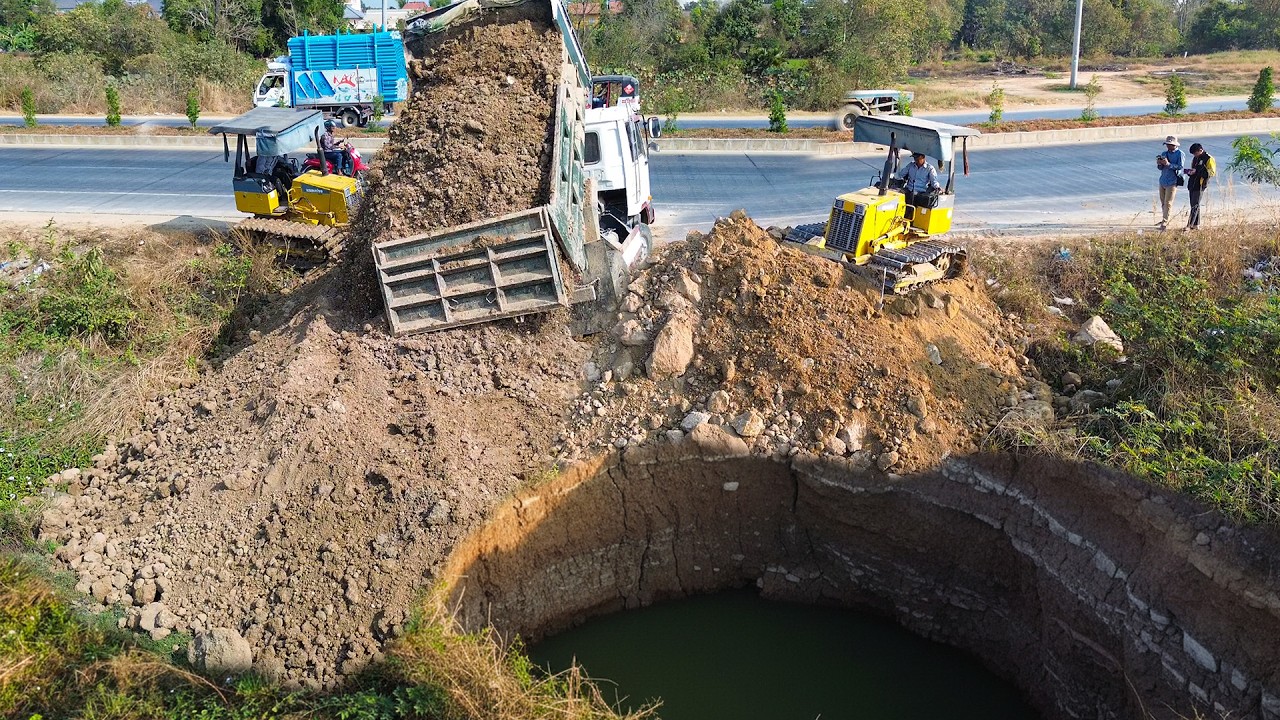 Amazing expert skill bulldozer pushes soil filling land with dump truck