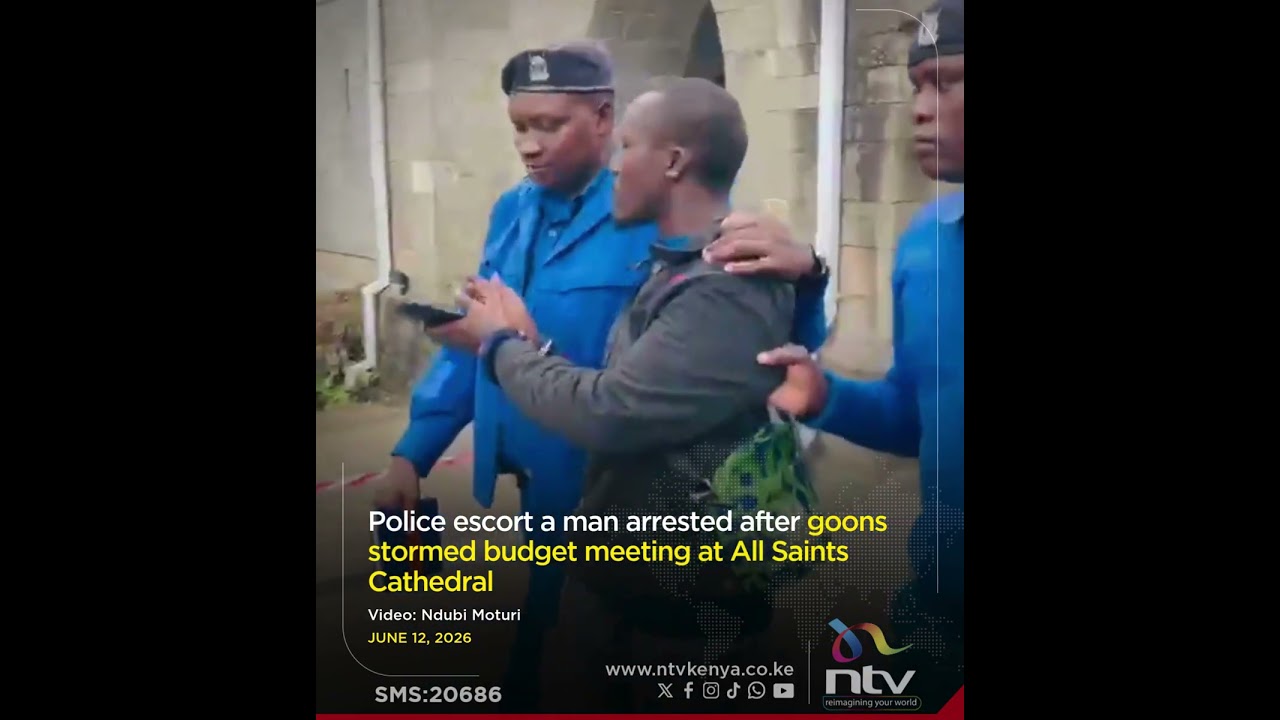 Police escort a man arrested after goons stormed budget meeting at All Saints Cathedral