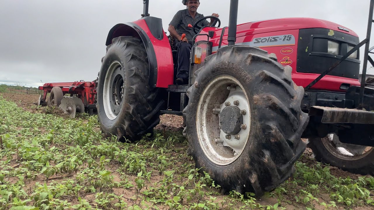 trator solís 75 traçado cortando terra na chuva no sítio conceição