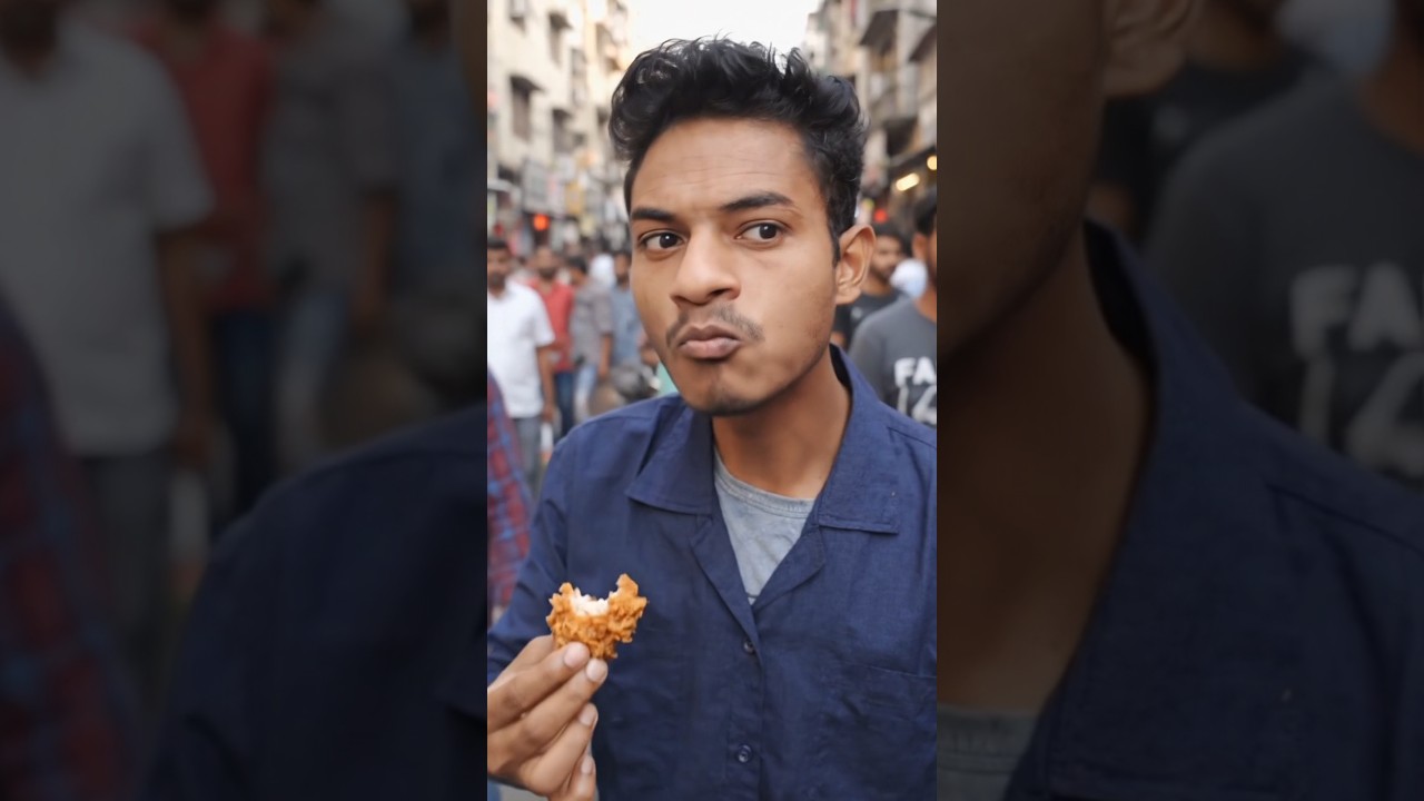 A boy is eating chicken in a crowd on the road. 