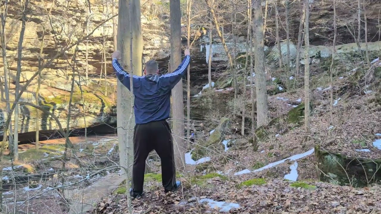 Qigong Near The Edge Of The High Rocks With Thawing Waterfall 