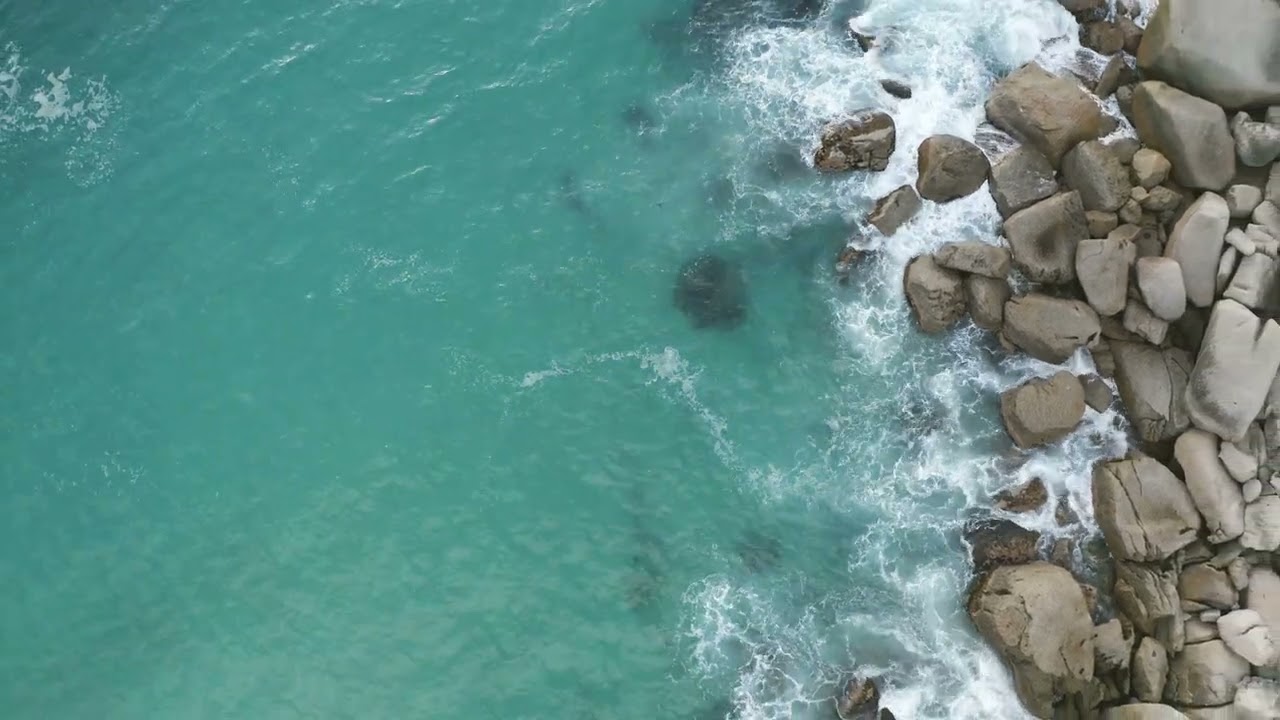 Aerial shot of deep blue ocean water and foamy waves  sea waves crash on the rocks of the coast crea
