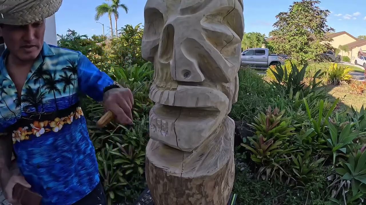 Tiki carver making a skull and marquesan tiki with chisels and power carving