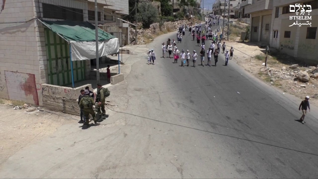 Israeli soldiers violently remove Palestinian teens from Hebron street to enable settler march