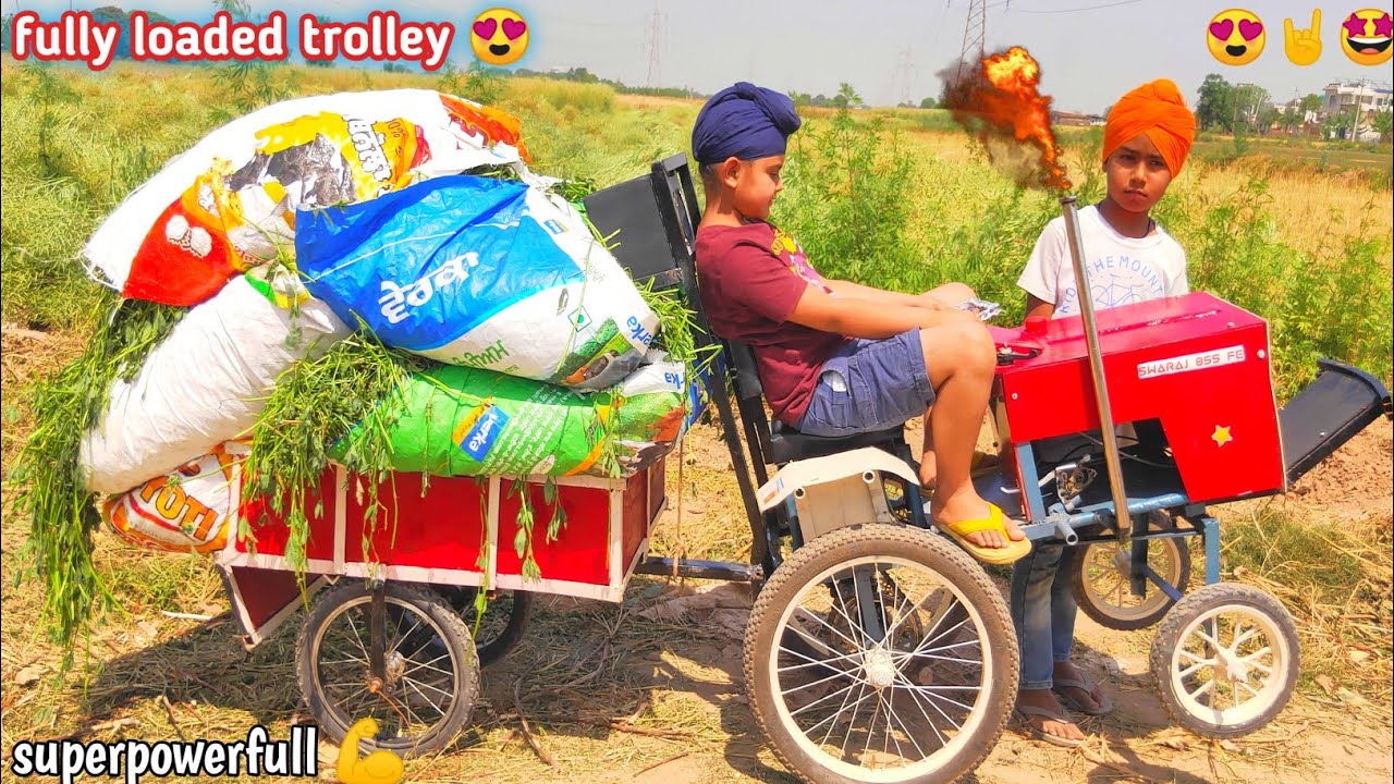 Homemade mini tractor pulling fully loaded trollet of grass. Diy tractor .