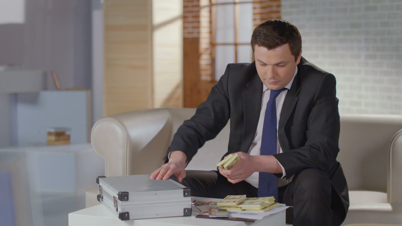 Greedy businessman takes dollar packs out of money case, laughs. Stock Footage