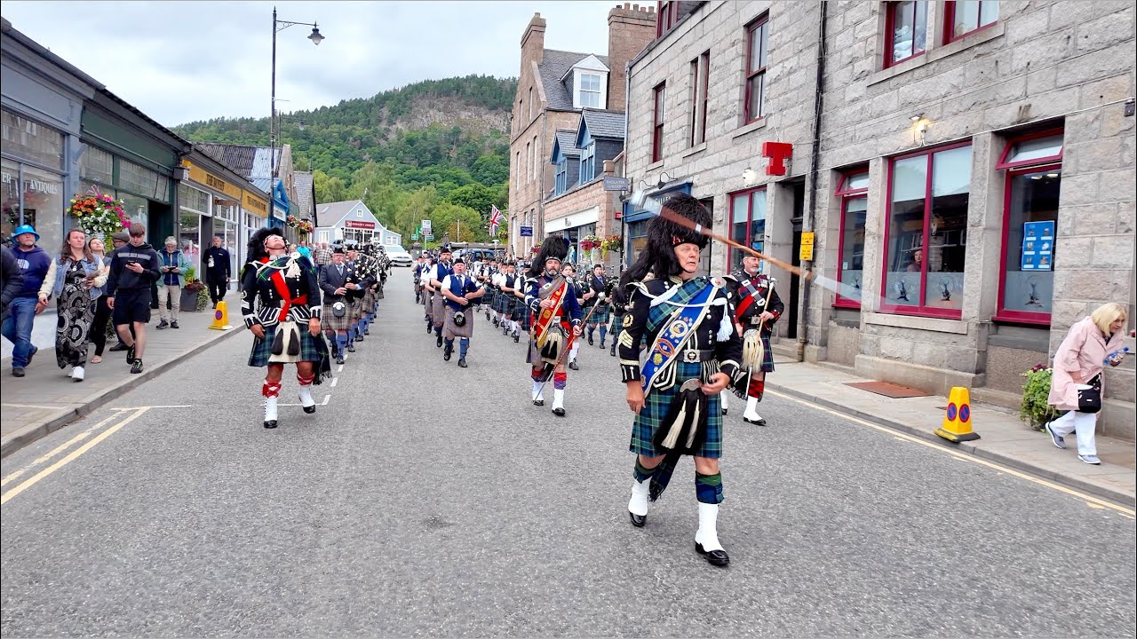 Drum Majors flourish leading combined pipe bands on the march after 2024 Ballater Highland Games