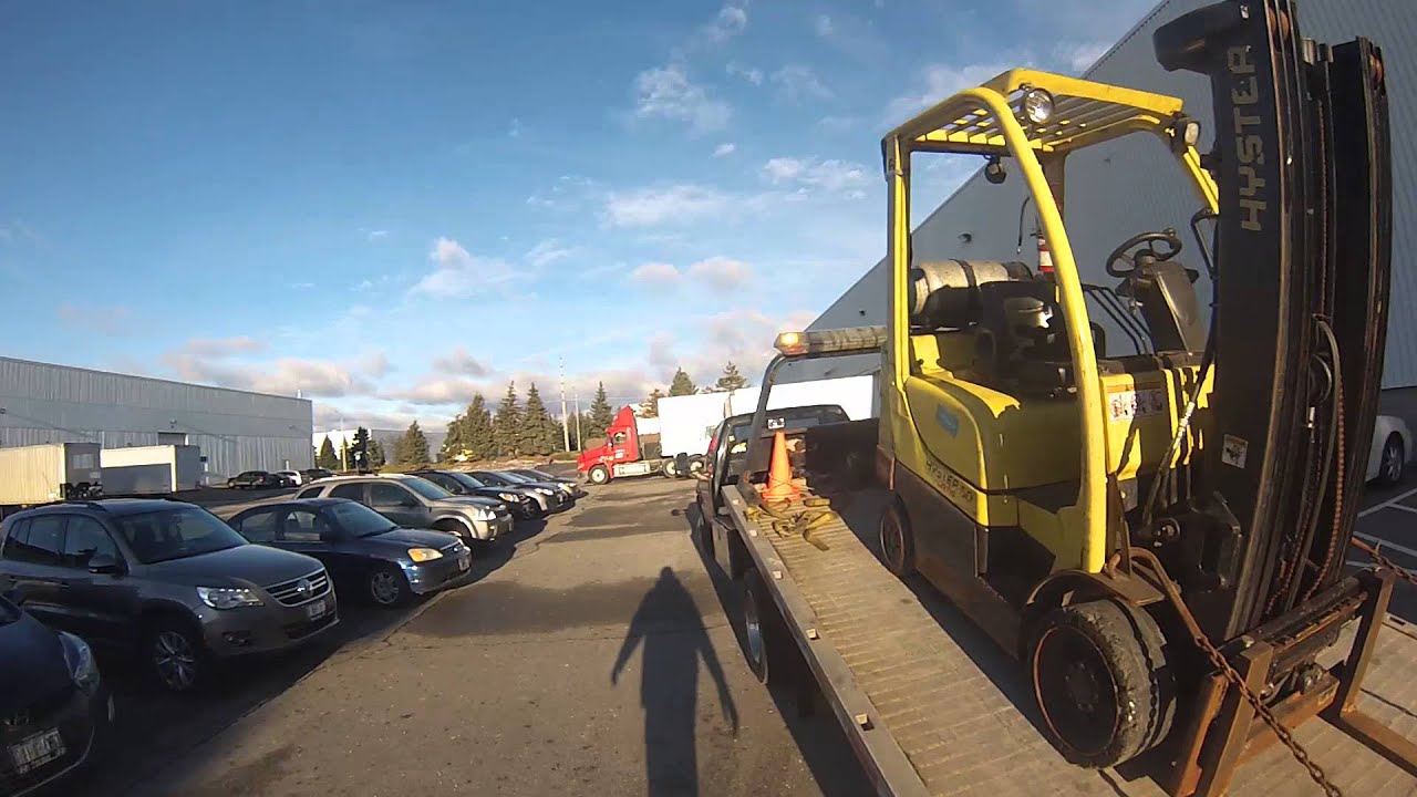 Moving Yellow Heavy Forklift on Flatbed Tow Truck