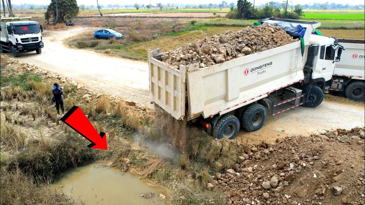 New project Landfilling by dump truck wheel 10 unloading soil with Heavy bulldozer SHANTUl pushing.