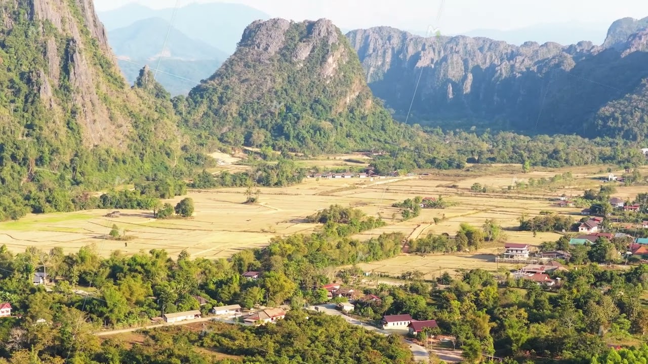 Aerial perspective of zipline over lush rainforest canopy in Vang Vieng, Laos with majestic mountain