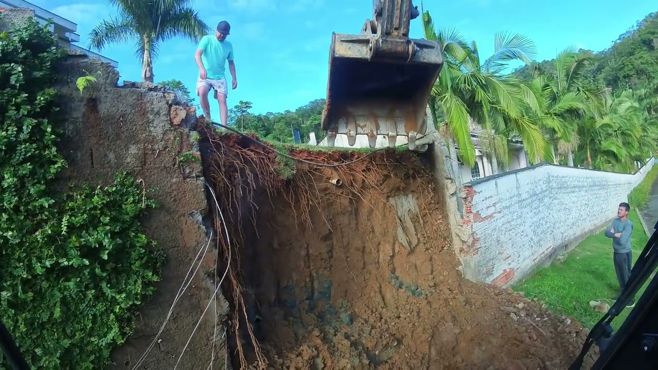 escavadeira demolindo parte de murro