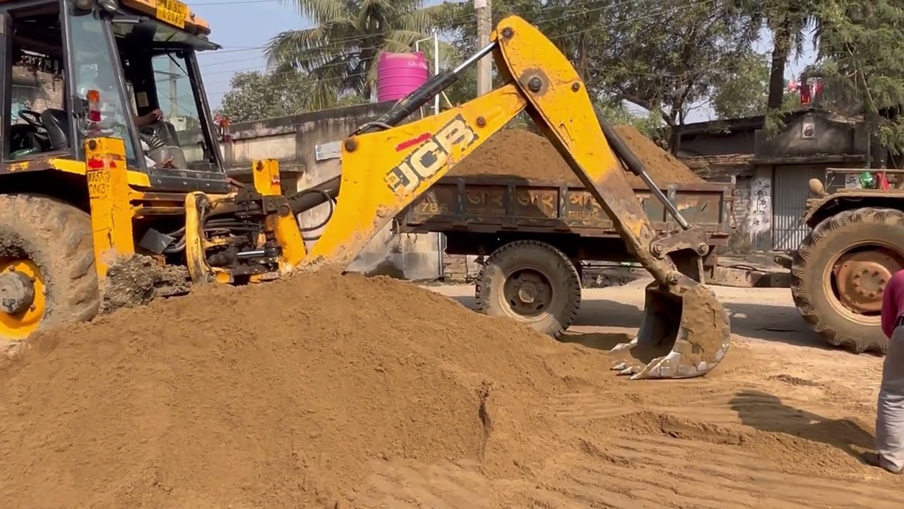We are loading sand into the Red Swaraj tractor with a JCB3DX 
