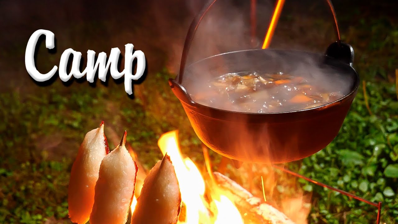 焚き火に鉄鍋吊るして串で炙り焼き