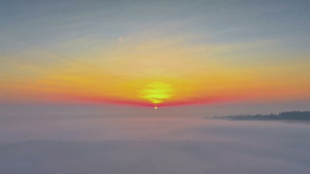 Die Sonne erhebt sich langsam über einem Meer aus Nebel.