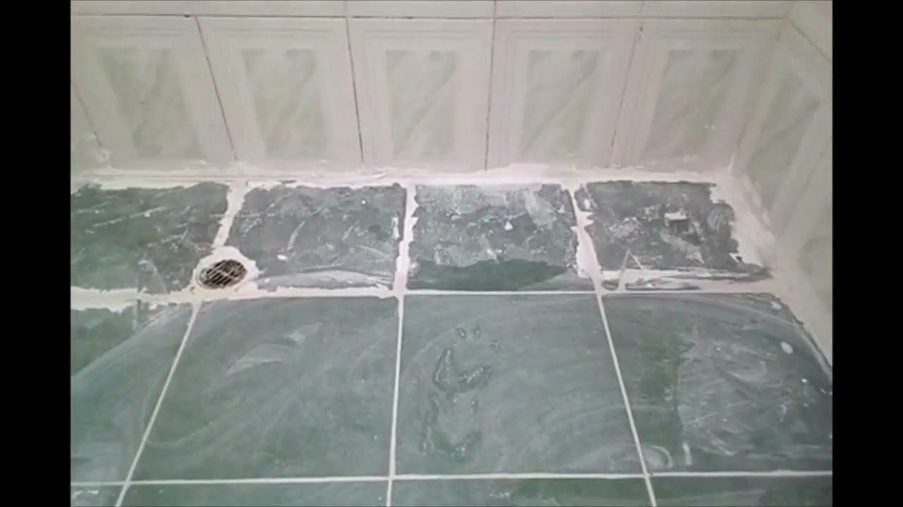 Reparación de juntas de baldosas en piso de ducha de baño con cemento blanco
