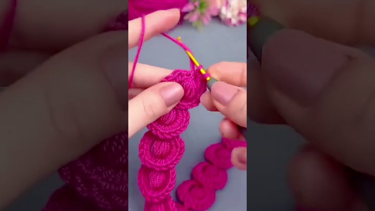 crocheting a vibrant pink yarn into a series of interconnected circles using a small metal hook tool