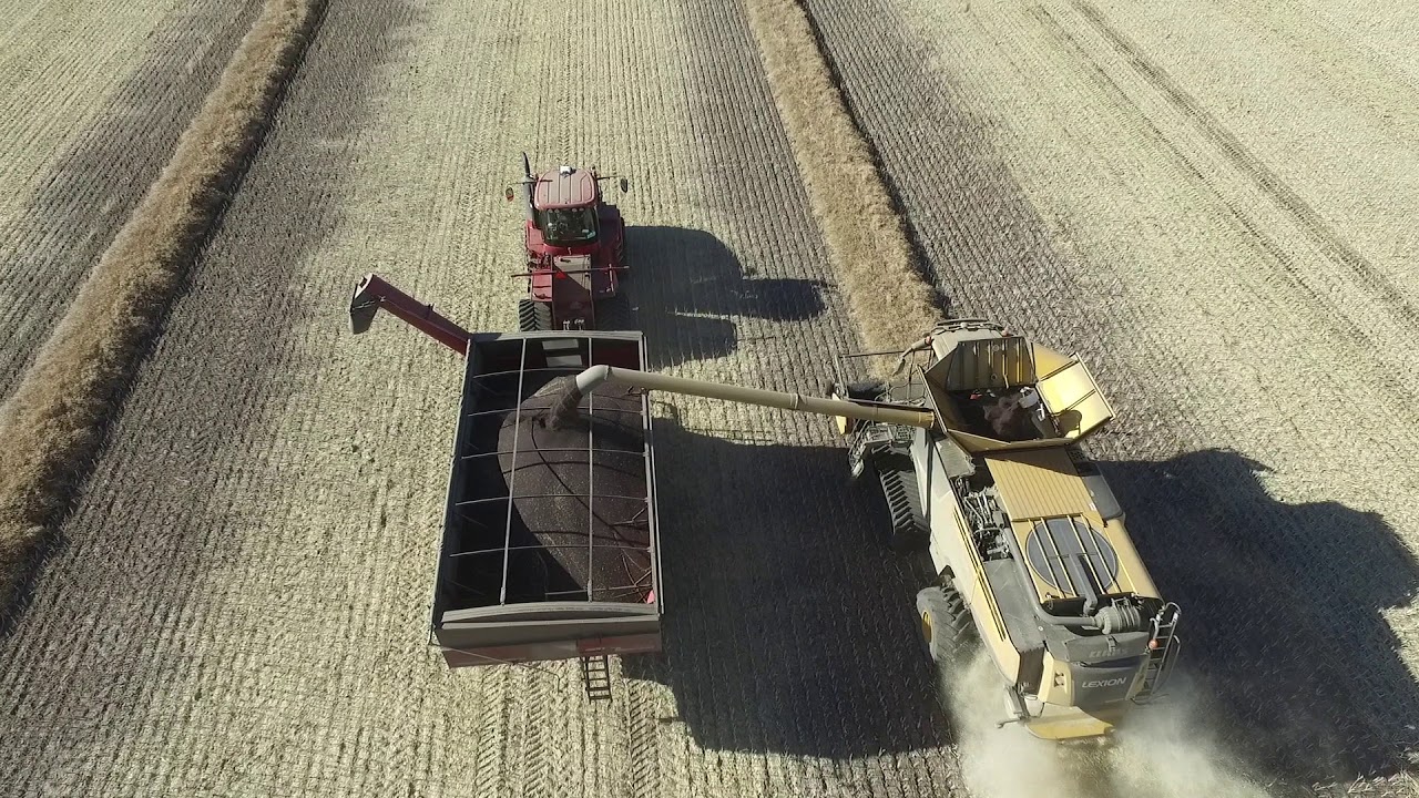 A CLAAS 780 combine unloading into a CASE 620 tractor