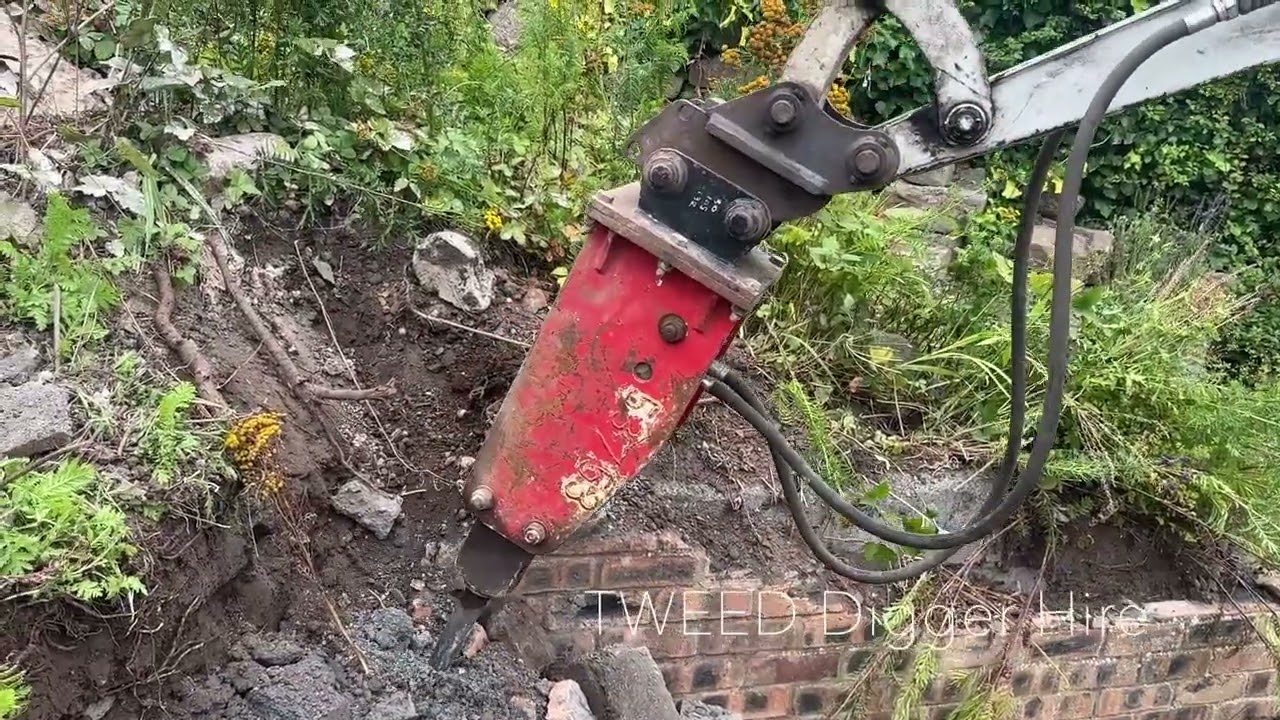 Mini Digger using Concrete breaker on a brick and stone wall