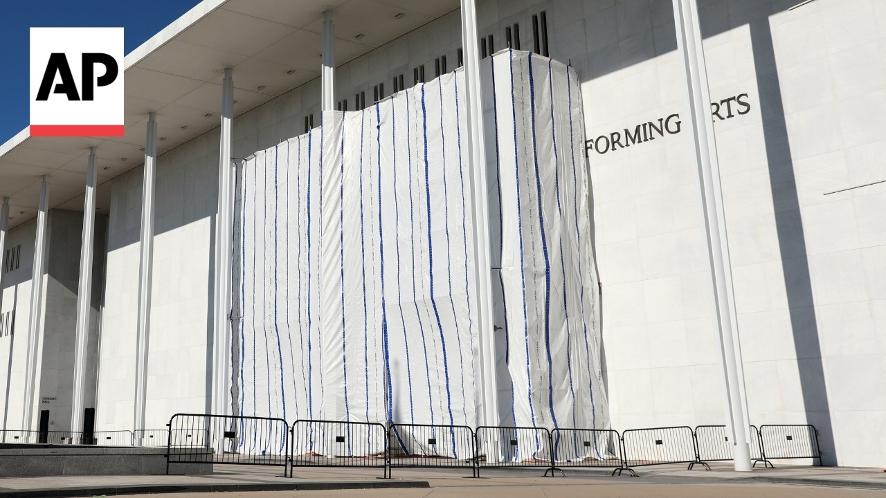 Workers cover the Kennedy Center signage before removing Trump's name