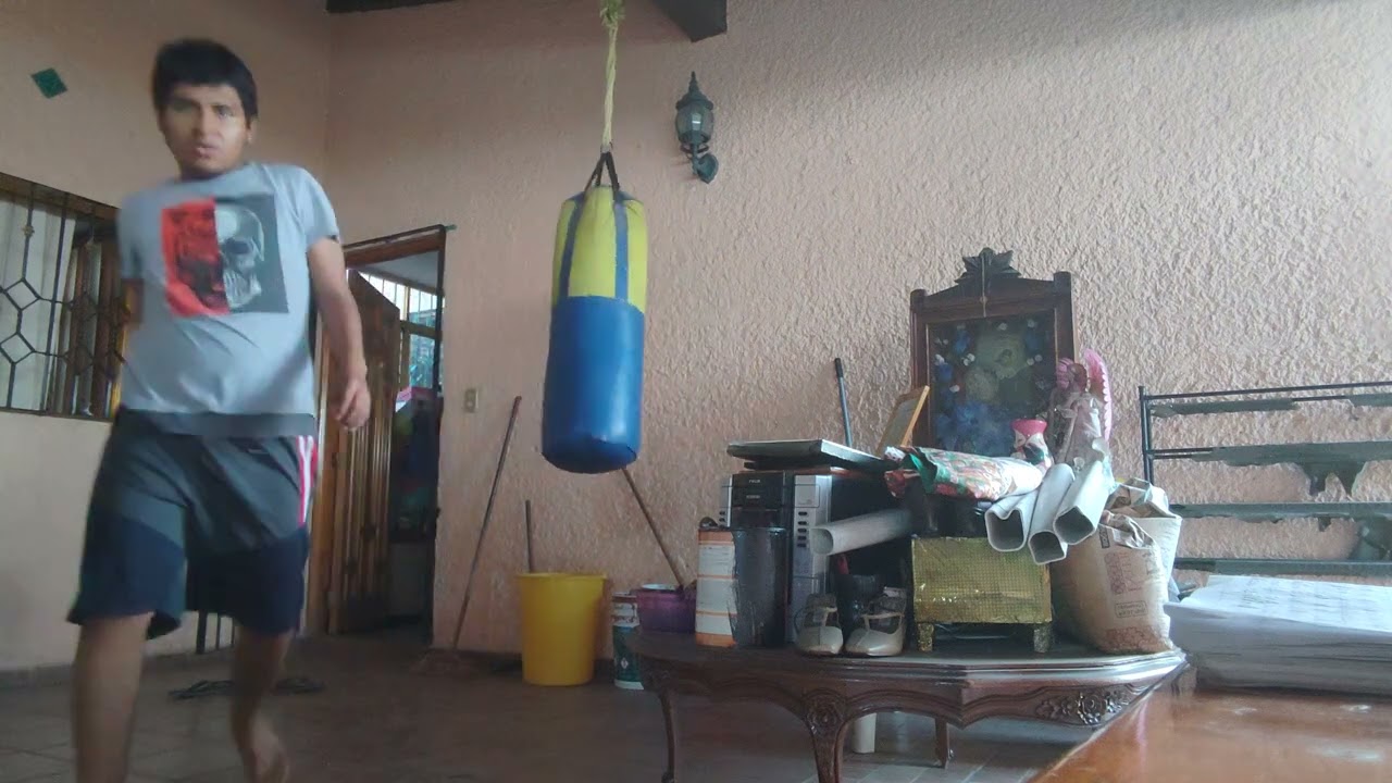 Entrenando en la casa de mi abuela dándole patadas al costal y codazos 