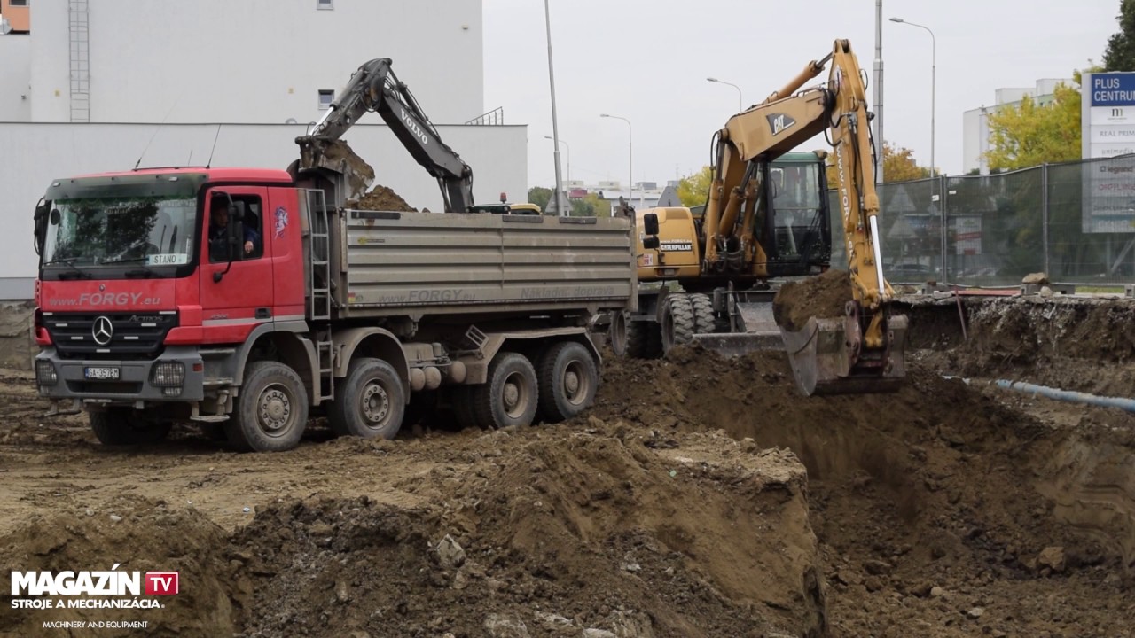 Wheel excavator CAT M318C digging and loading dirt to Mercedes-Benz ACTROS 4144 dump truck