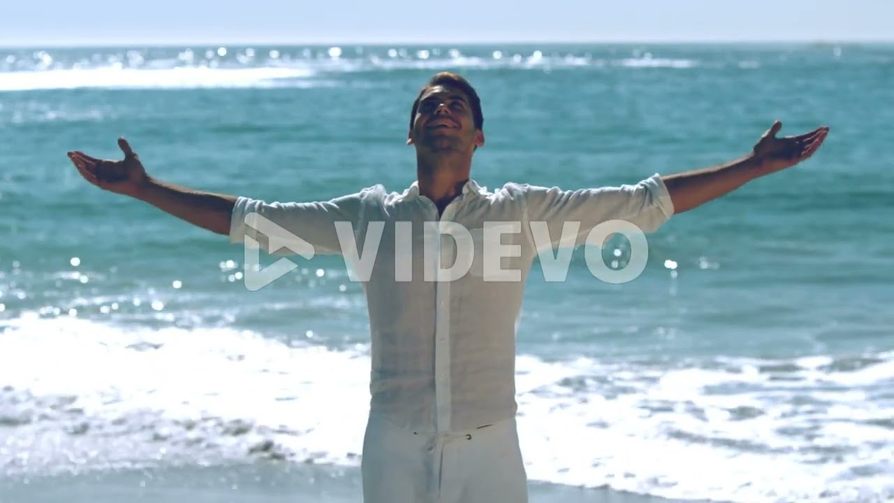 Handsome calm man practicing yoga on the beach