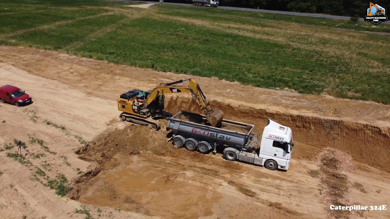 Caterpillar 324E in operation at road building with dump trucks-also drone with DJI mini 2 drone