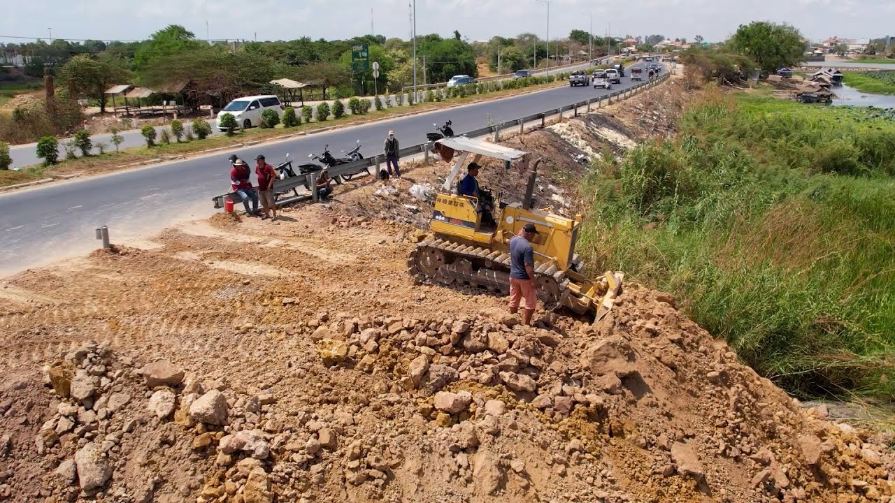 New project landfill up processing bulldozer and team dump truck pouring, push soil near the highway