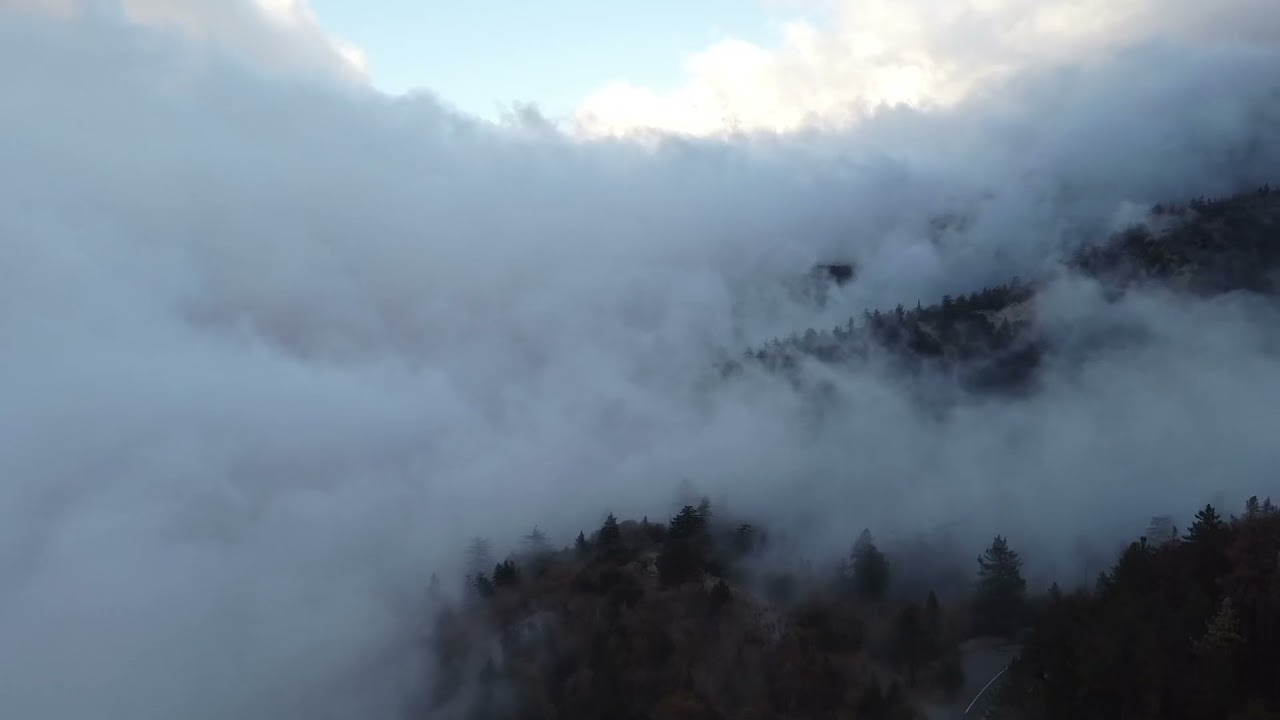Drone flight through clouds in the mountains