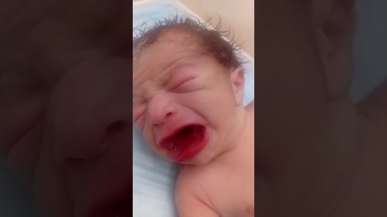 The newborn baby is expelling the substance from her mouth through saliva