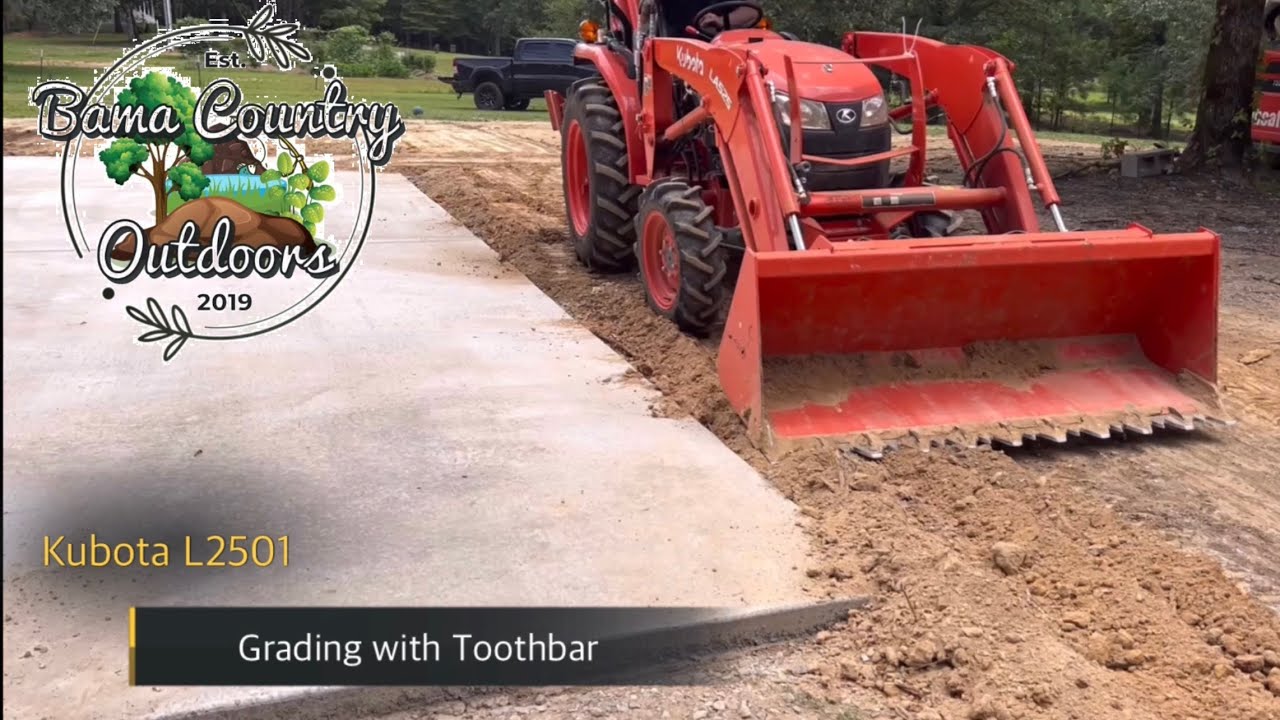 Kubota L2501 using piranha toothbar to grade around concrete driveway