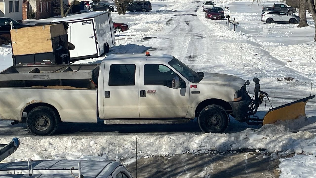 bulldozer & pickup trucks clearing neighborhood streets after snowstorm 