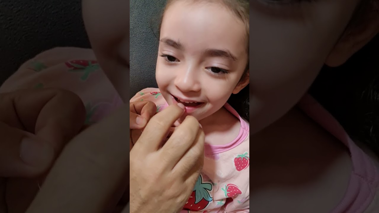 Papai tirando o primeiro dentinho da Isabella.