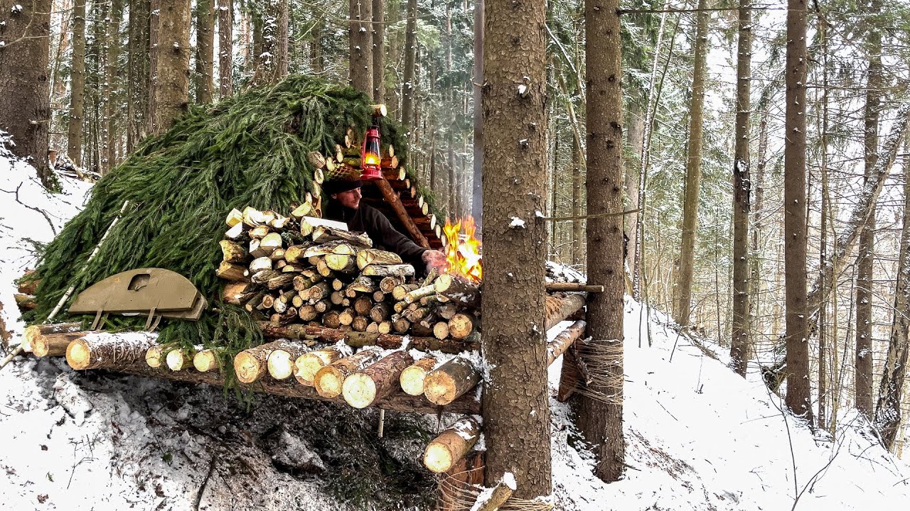 Construction of a comfortable log shelter on the mountainside. Bushcraft in a cold winter forest