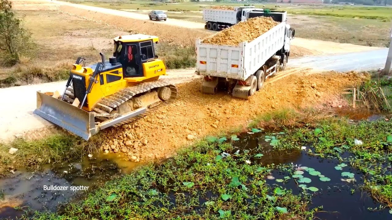Great job !! Heavy Dump truck unloading soil landfilling flooded with SHANTUI C2 dozer pushing soil 