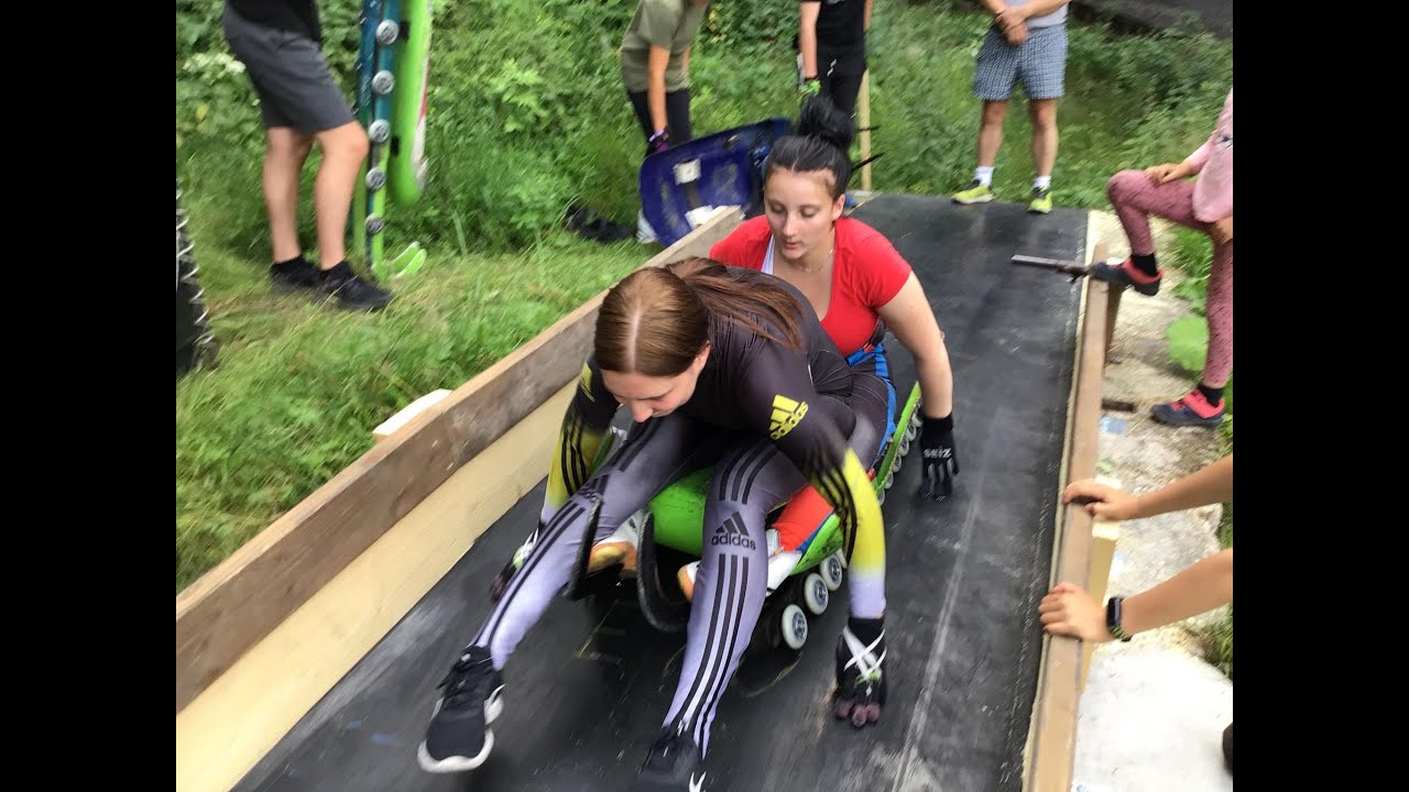 Young luge athletes training sledding on wheels and ice start in summer