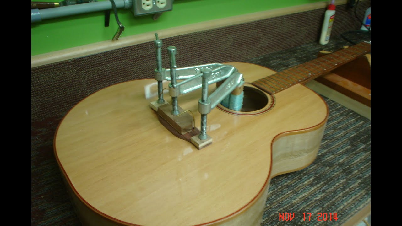Gluing a bridge on an acoustic guitar.