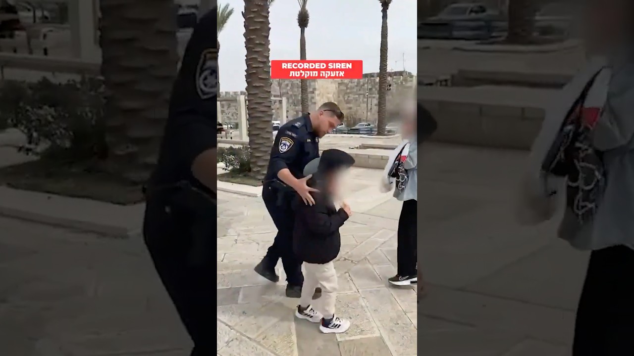 Israeli policeman protecting a Muslim family in Jerusalem during rocket fire